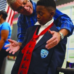 A member of the First United Methodist Church of St. Petersburg helps a student with his tie.