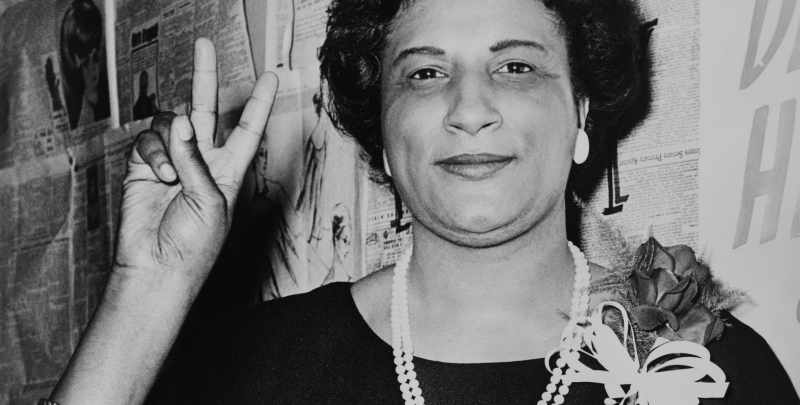Mrs._Constance_B._Motley_first_woman_Senator_21st_Senatorial_District_N.Y._raising_hand_in_V_sign.png